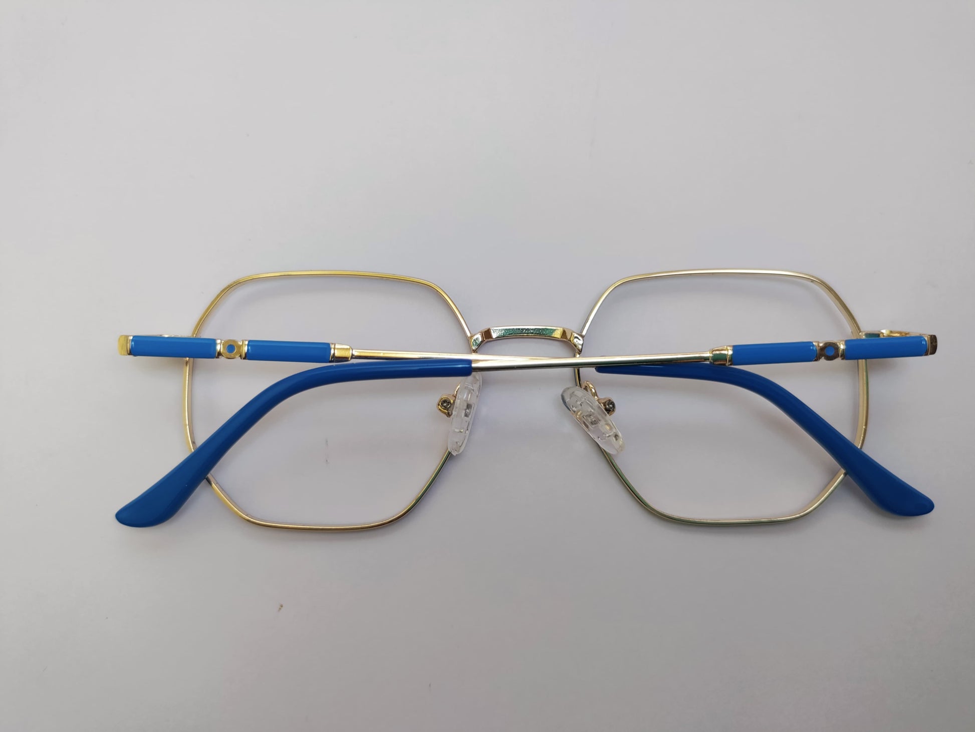 Eyeglasses with blue arms and gold frame on a light gray background